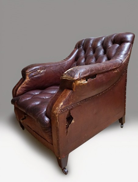 Schuin vooraanzicht van een antieke Edwardiaanse herenfauteuil op wieltjes als restauratieproject