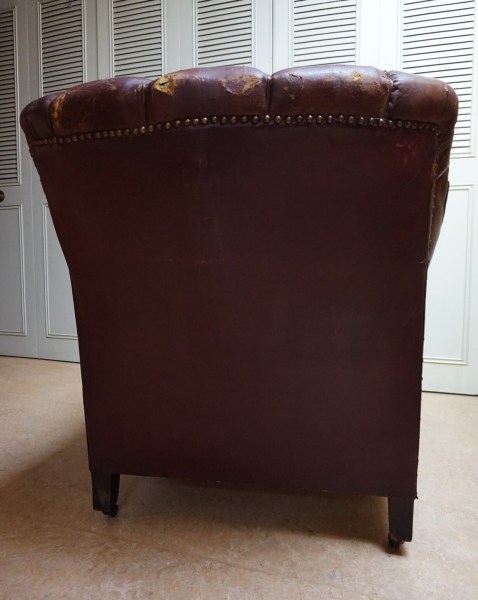Straight back view of an antique Edwardian gentleman's chair showing stud details and wear