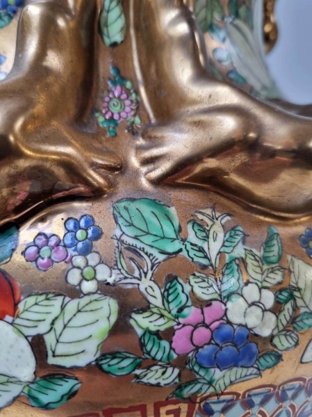 Detailed view of the gilded relief handles and hand-painted floral gilt design on a Chinese porcelain table lamp