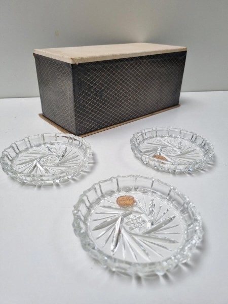 Dessous de verre vintage en verre pressé de style mid-century avec un motif étoilé, disposés devant leur boîte d'origine 