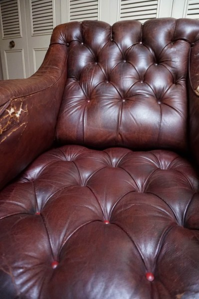 Gros plan du dossier capitonné en cuir marron d'un fauteuil club Chesterfield vintage