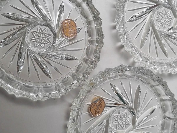 Nahaufnahme von drei Vintage-Untersetzern aus Kristallglas aus der Mitte des 20. Jahrhunderts mit einem aufwendigen Sternenmuster, wobei zwei noch ihre originalen goldenen Etiketten von Bohemia Glass tragen