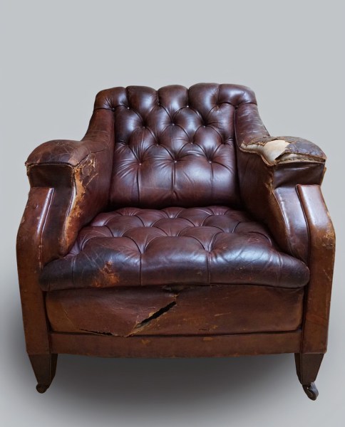 Recht vooraanzicht van een oude vintage gecapitonneerde Engelse Chesterfield clubfauteuil van bruin leer