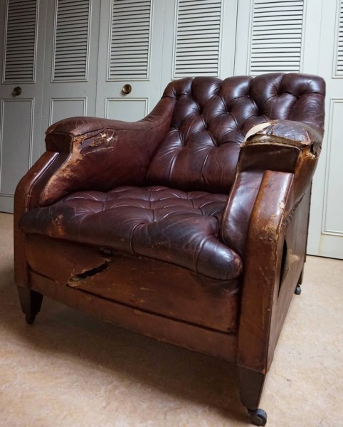 Vista frontale angolata di una poltrona Chesterfield vintage in pelle marrone rovinata da restaurare