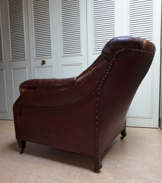 Left profile view of a heavily used leather library chair ready for restoration